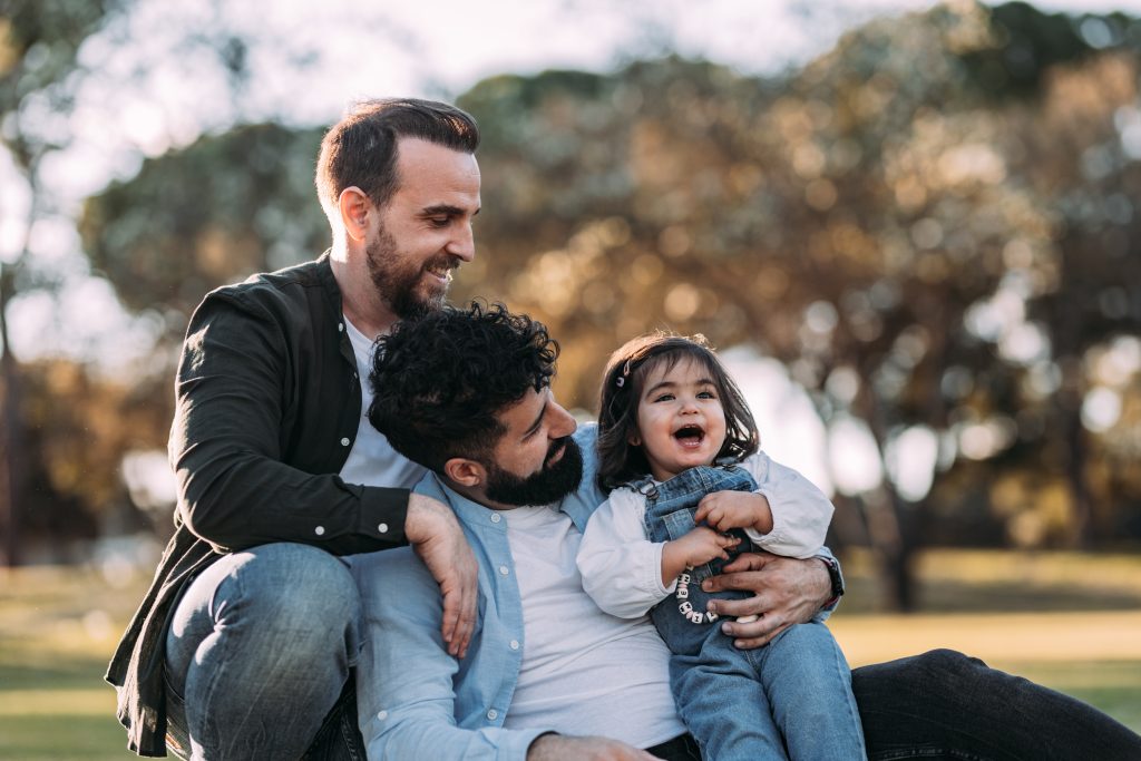 Gay couple enjoying in the park with their young daughter.