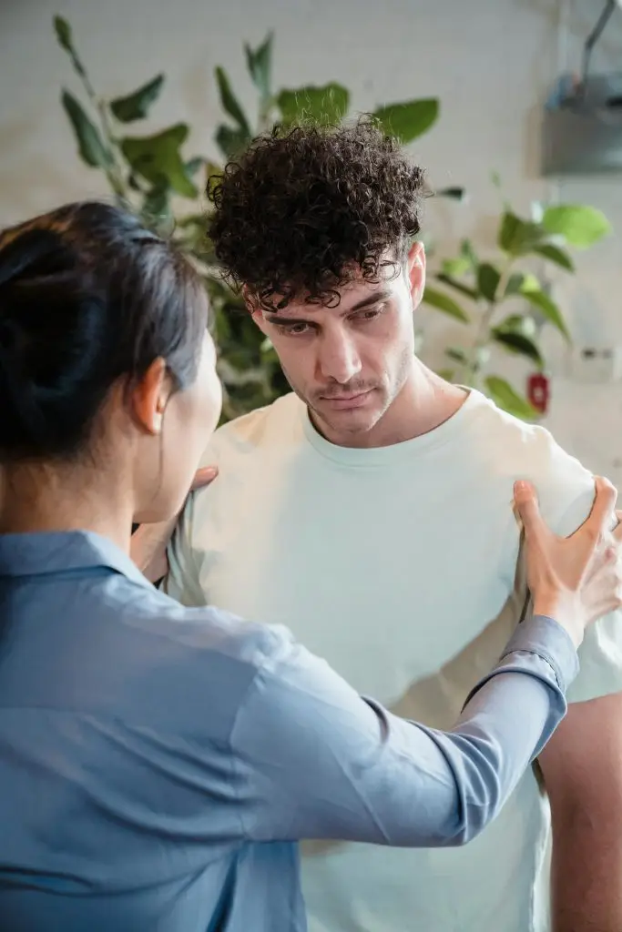 Person standing calmly with partner with hand on shoulder, symbolizing nervous system safety and connection during relationship conflict.